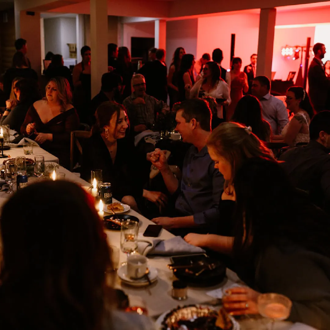 Wedding guests seated at reception tables in a warmly lit lodge event space.