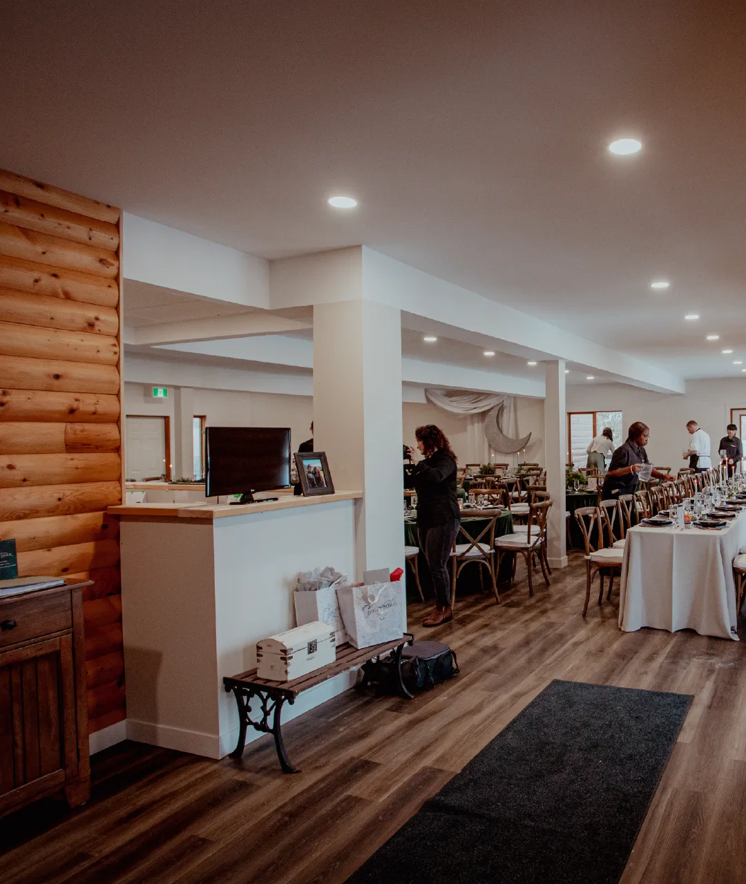 Entry area of the lodge event space with a service counter, gift bags and reception tables being set up in the background.