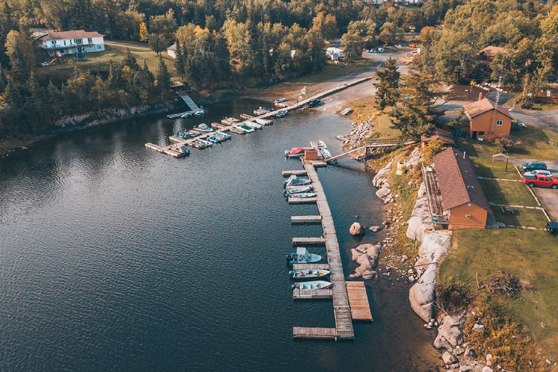 Aerial view of Perch Bay marina with docks, boats, cabins and rocky shoreline.