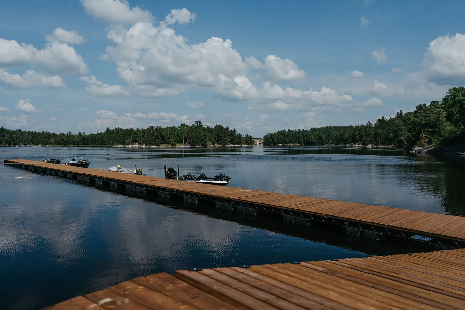 Wooden marina dock extending over calm water with boats tied alongside.