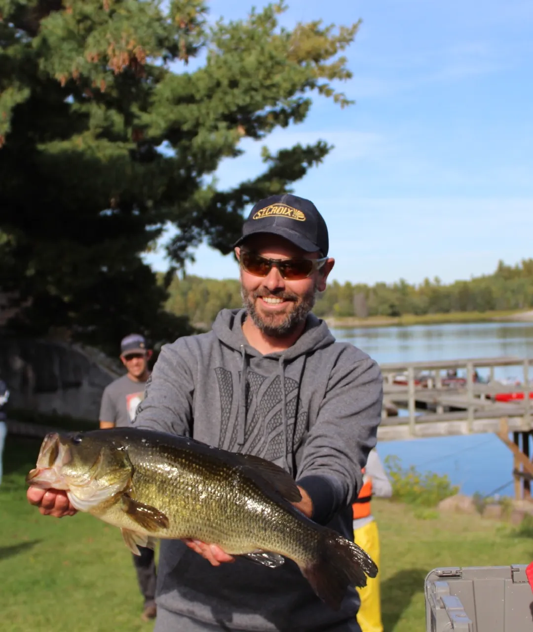 Person holding a large fish near the dock and water at Perch Bay.