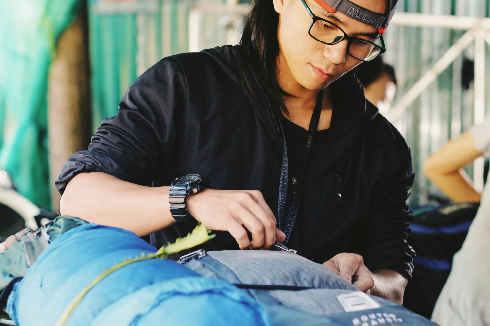 Person packing or adjusting a blue sleeping bag and outdoor gear.