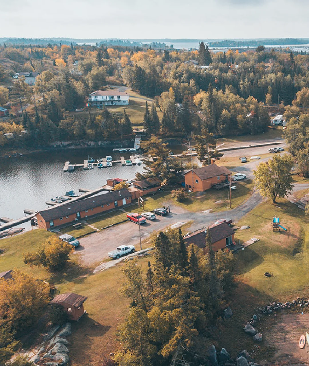 Aerial view of Perch Bay Resort with cabins, marina docks, boats and surrounding trees.