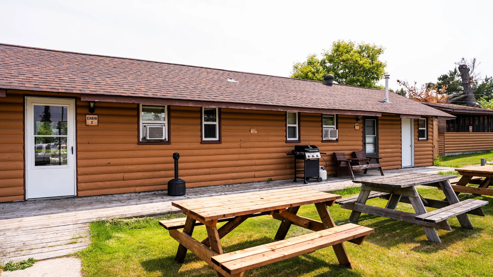 Exterior of the Dockside Cabins with picnic tables, barbecues, and cabin doors facing a shared grassy area.