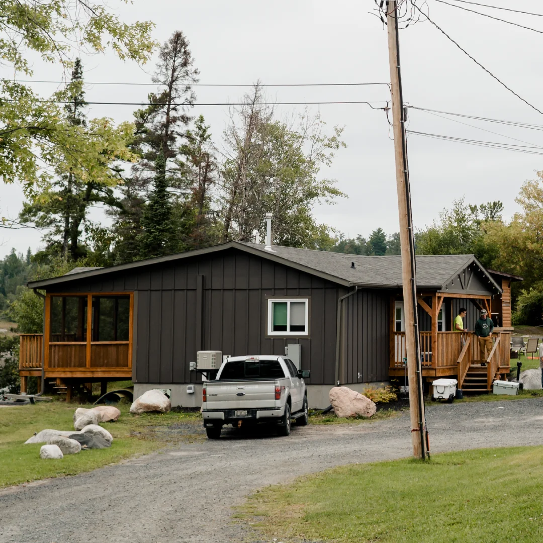 Cozy, contemporary wooden cabin interior with a bed, large windows, and a scenic view of mountains and nature.