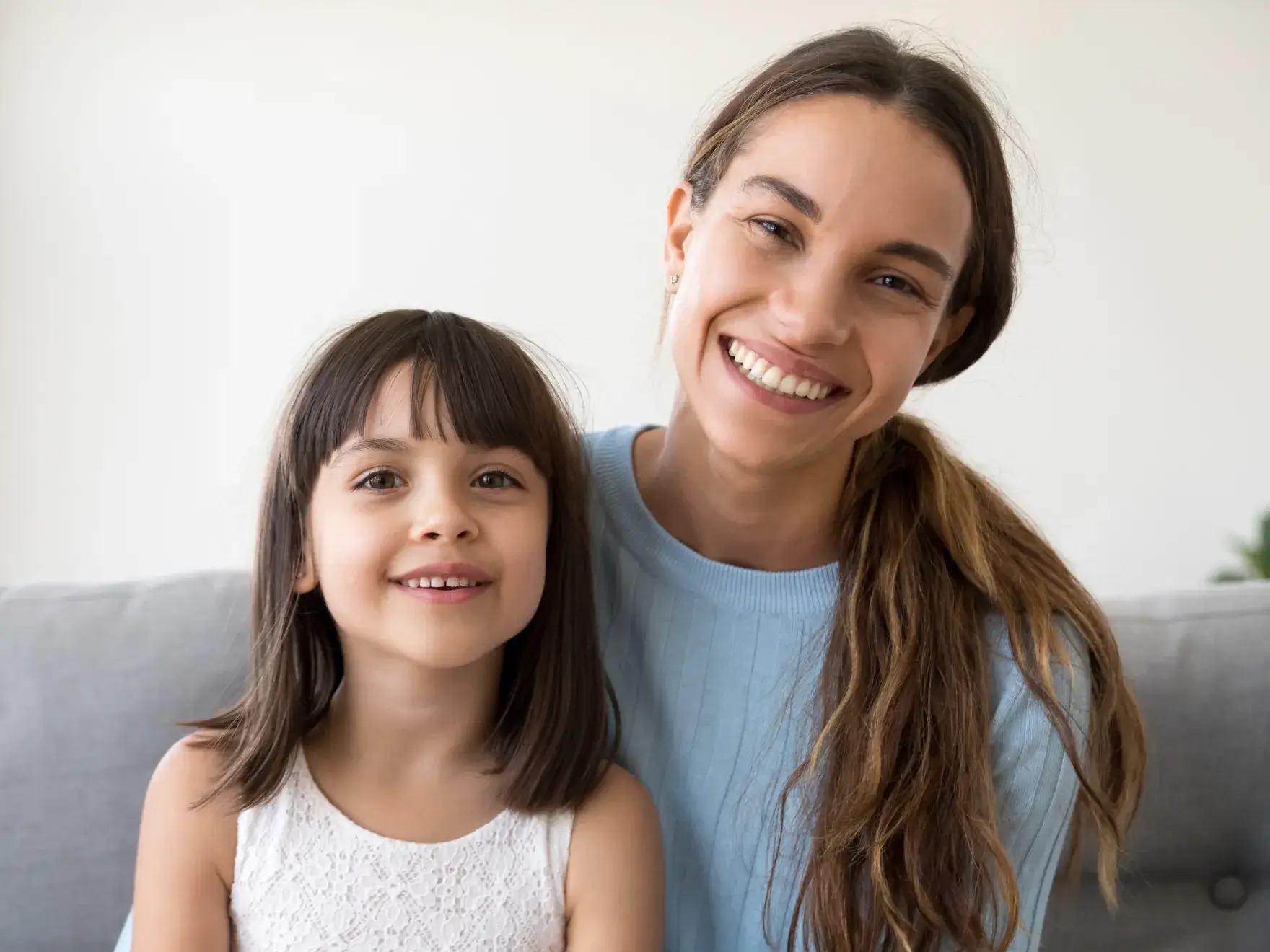 a woman and a little girl sitting on a couch
