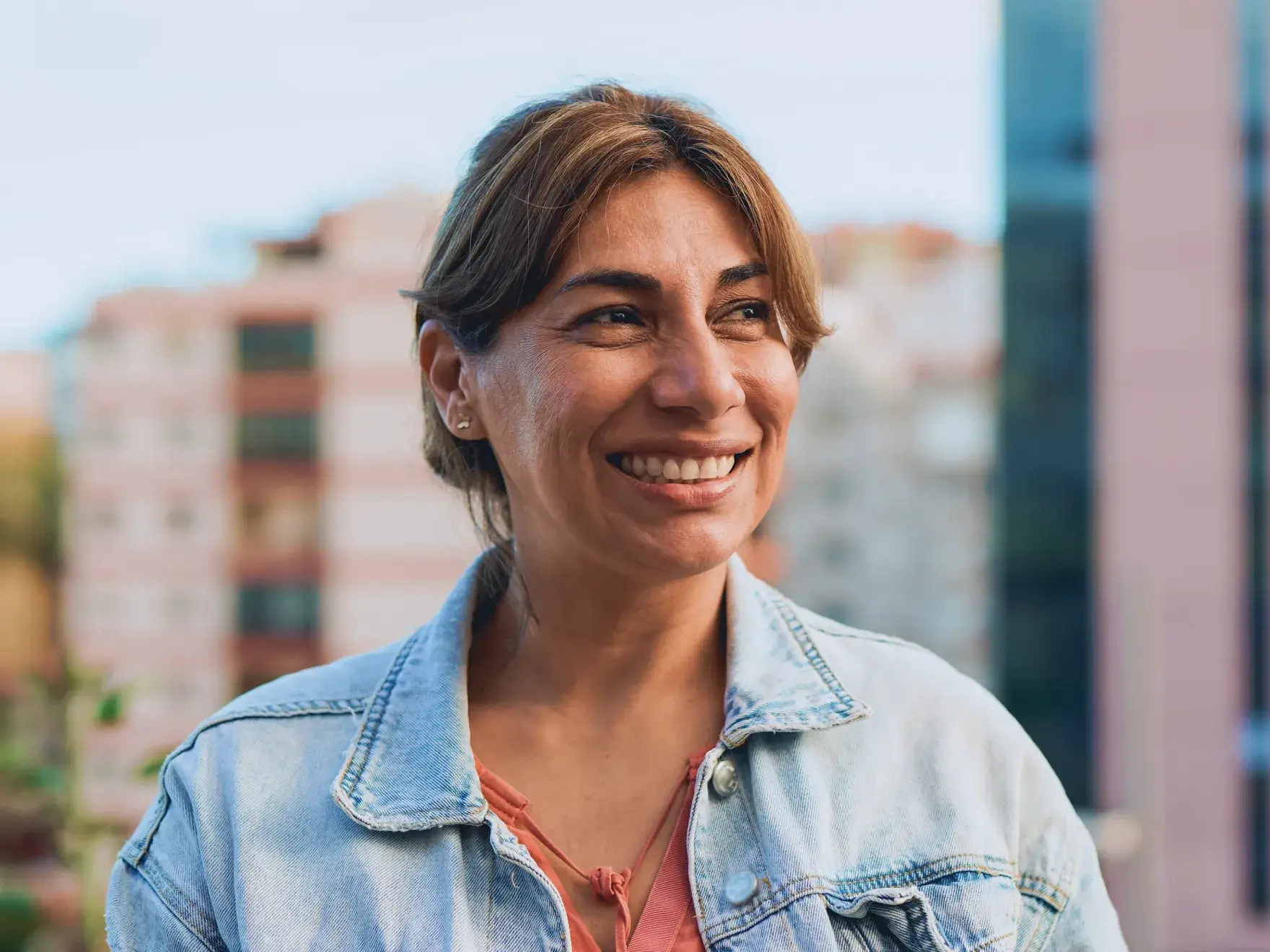 a woman in a denim jacket smiling at the camera