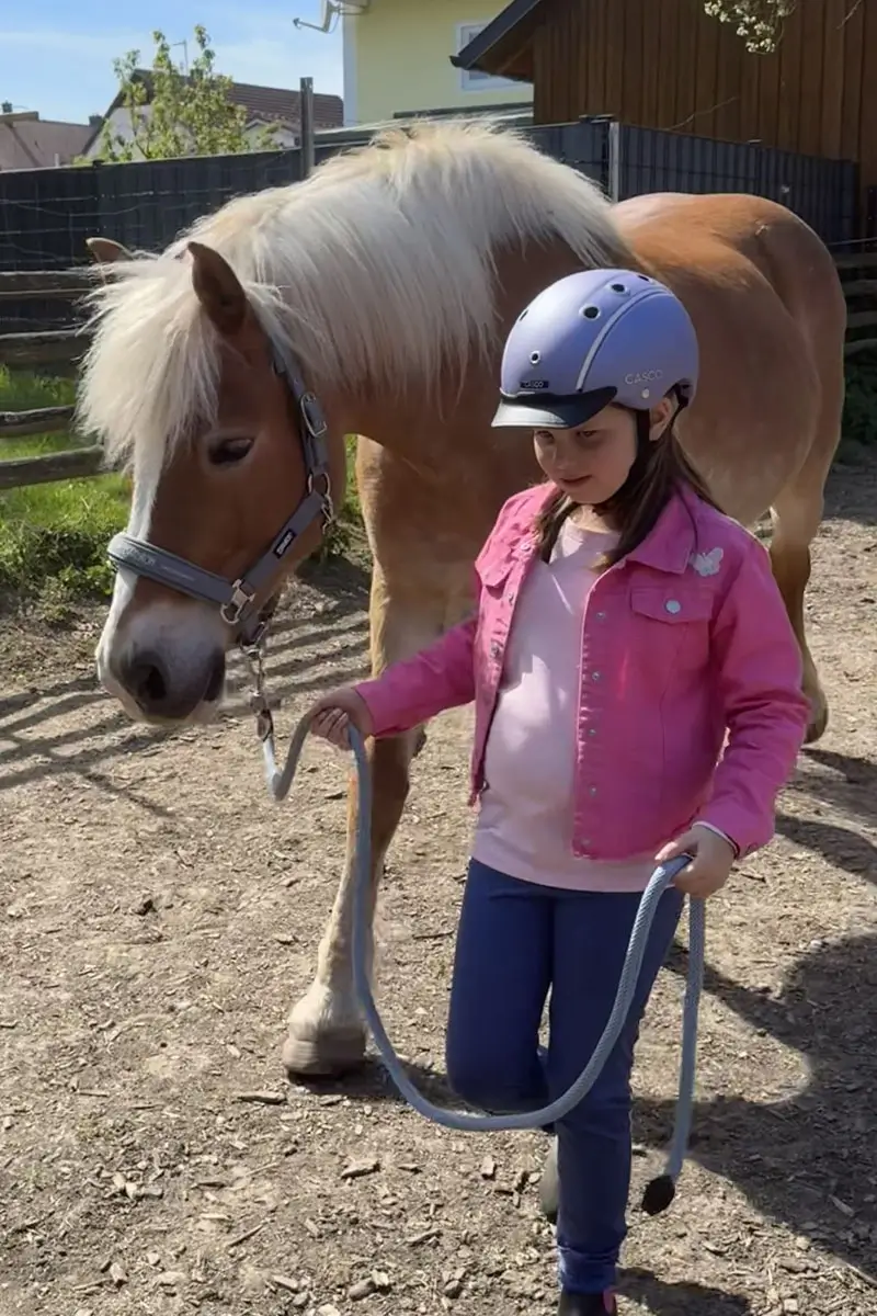 Kind führt eigenständig ein Pferd.