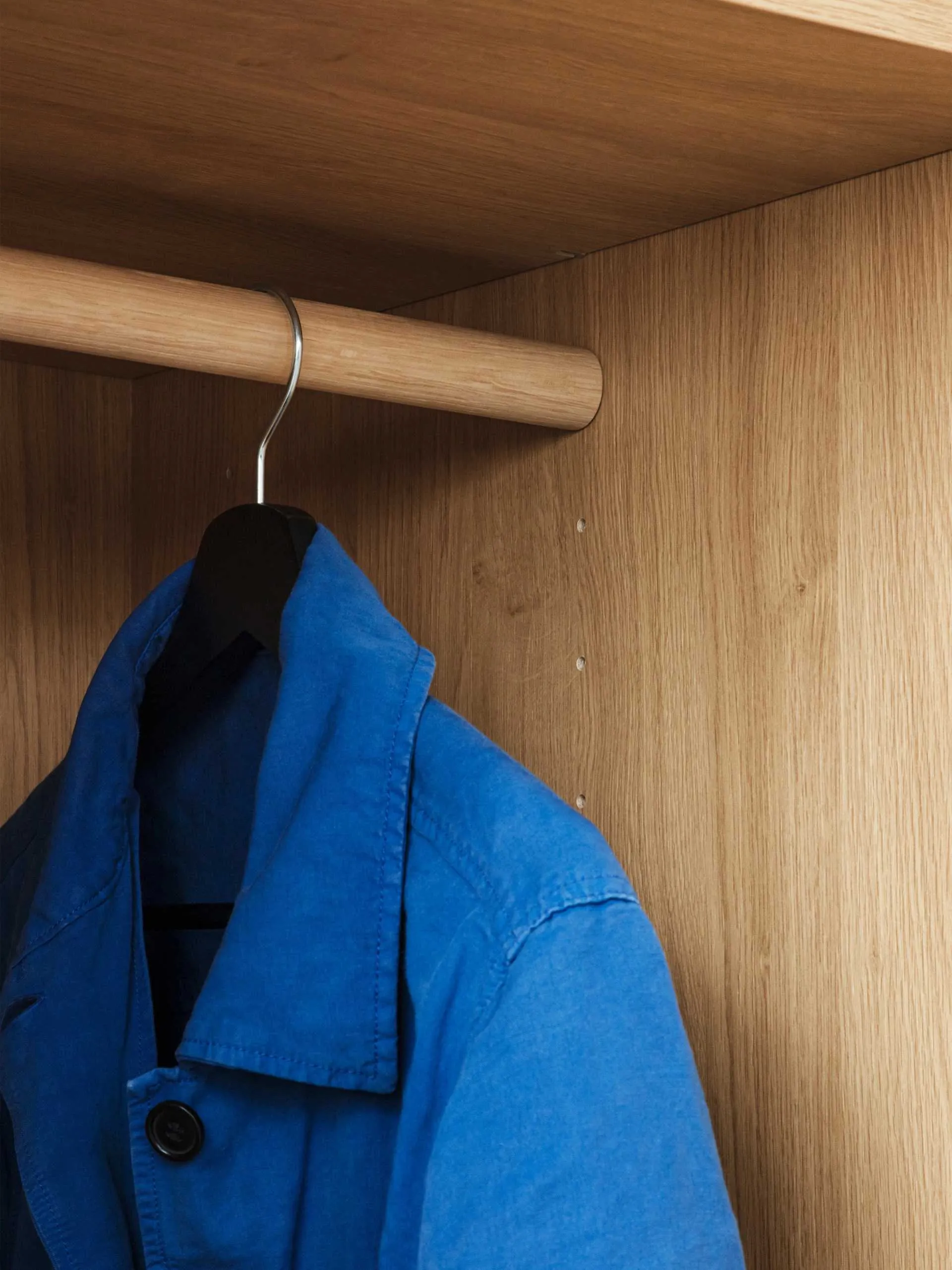Blue jacket on a hanger in a wooden wardrobe.