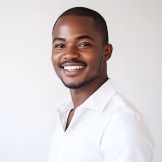Smiling young man wearing a white shirt against a plain light background.