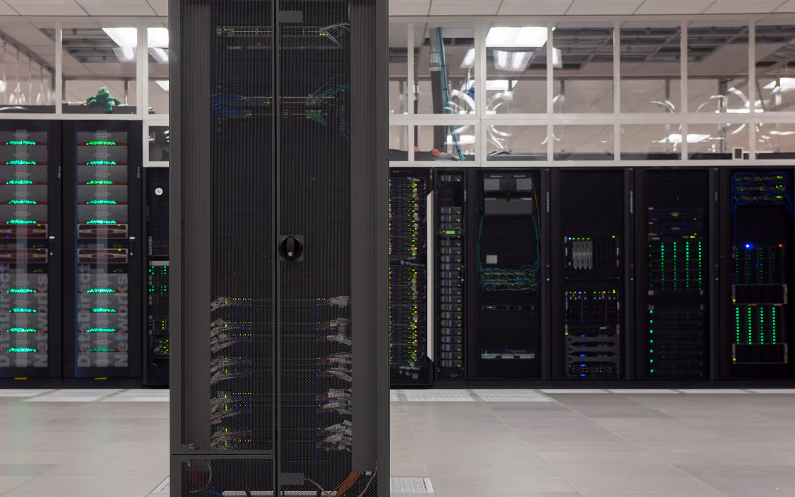 Large server racks with illuminated network equipment inside a modern data center room.