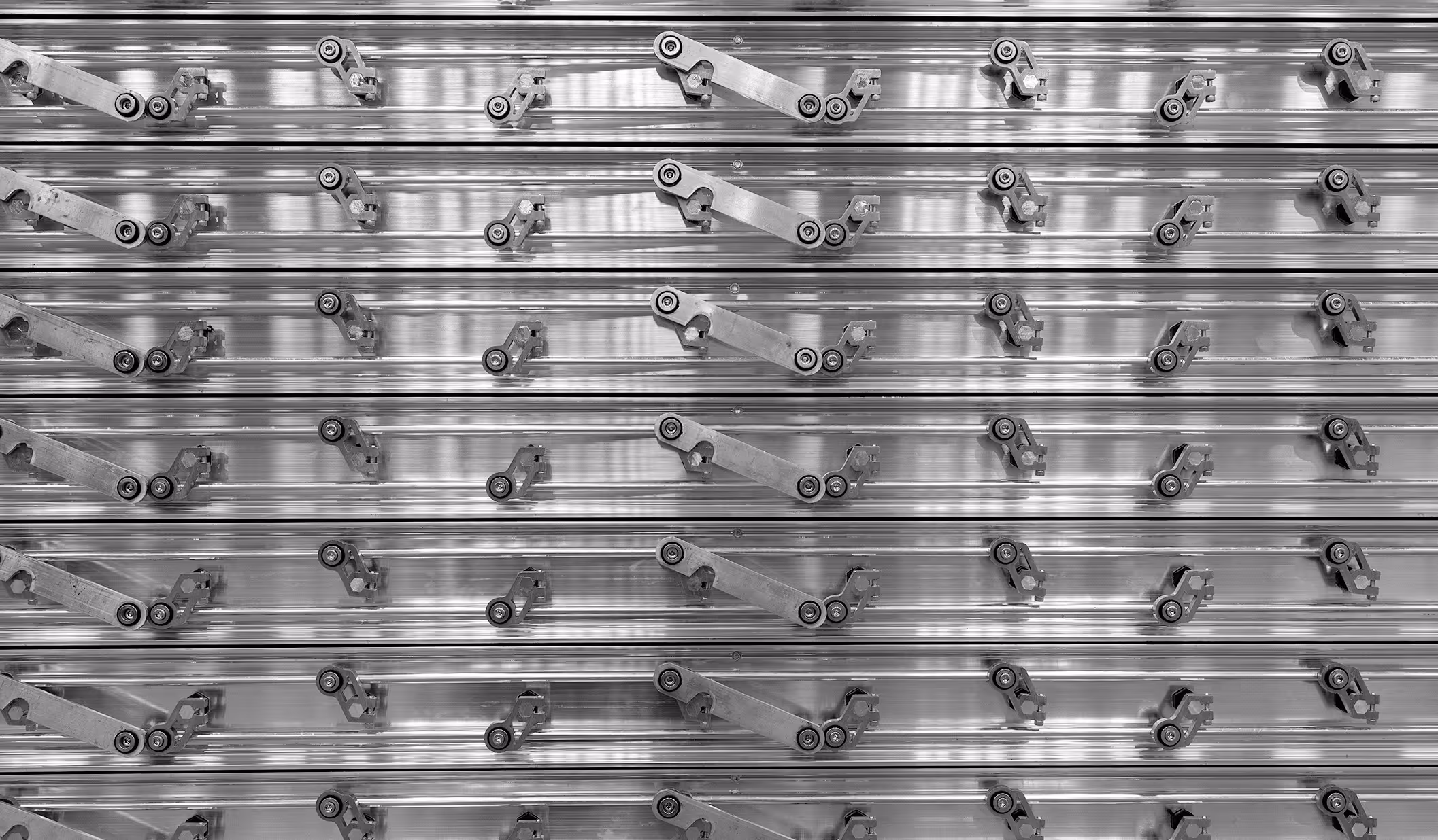 Close-up of metal conveyor belt components arranged in parallel rows with roller mechanisms.