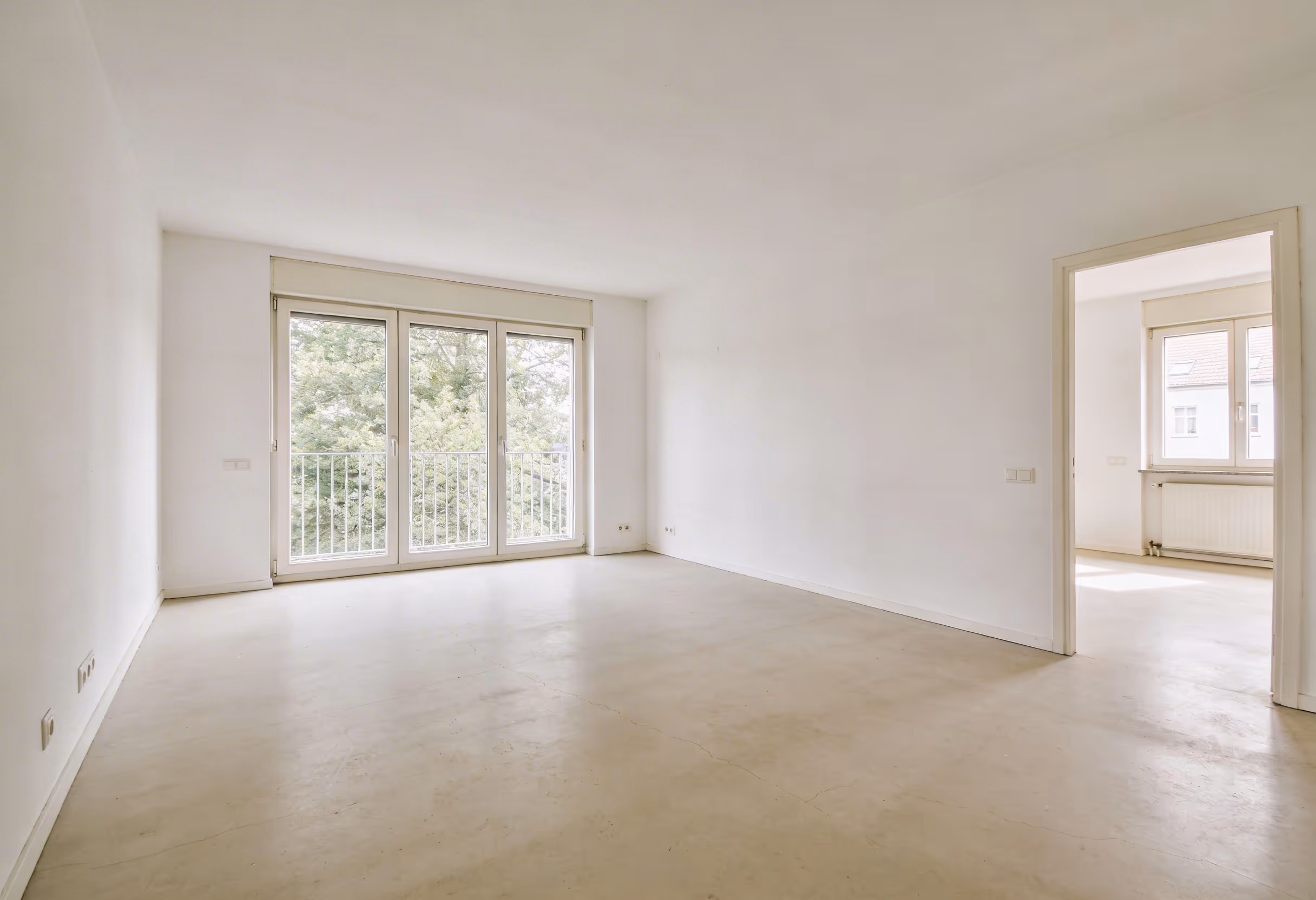 Leerer Raum mit großen bodentiefen Fenstern und Tür zu einem weiteren hellen Zimmer nach einer Haushaltsauflösung