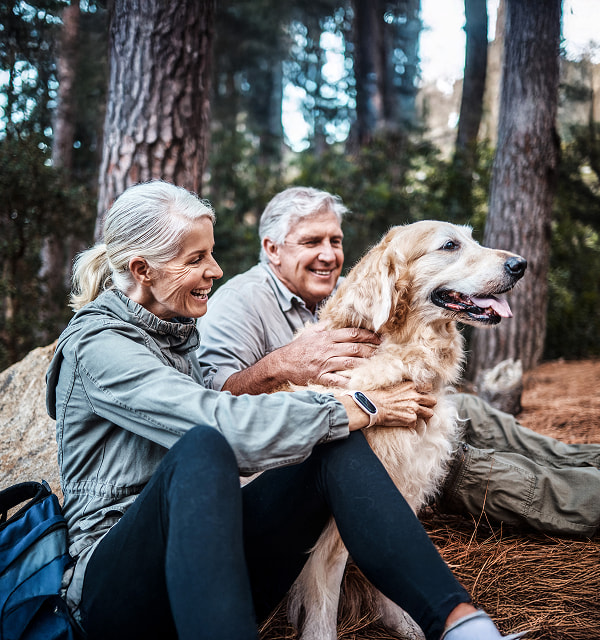 Retired couple on a hike through a forest with their dog