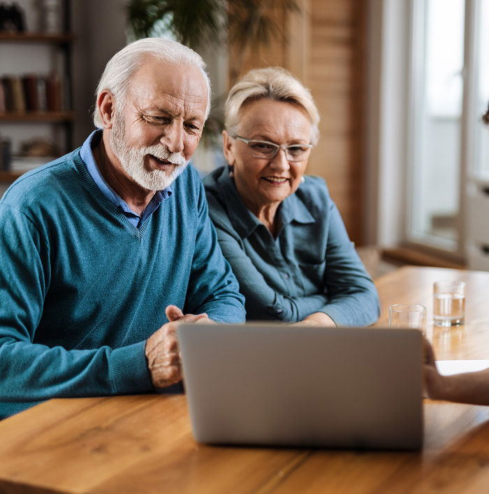 Retired couple watching the news at their dinner table in the morning