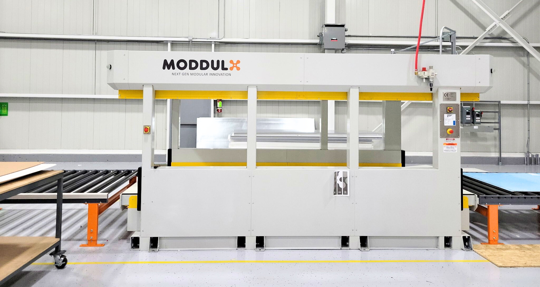 Large industrial MODDULX machine with conveyor belts on either side in a clean factory setting.