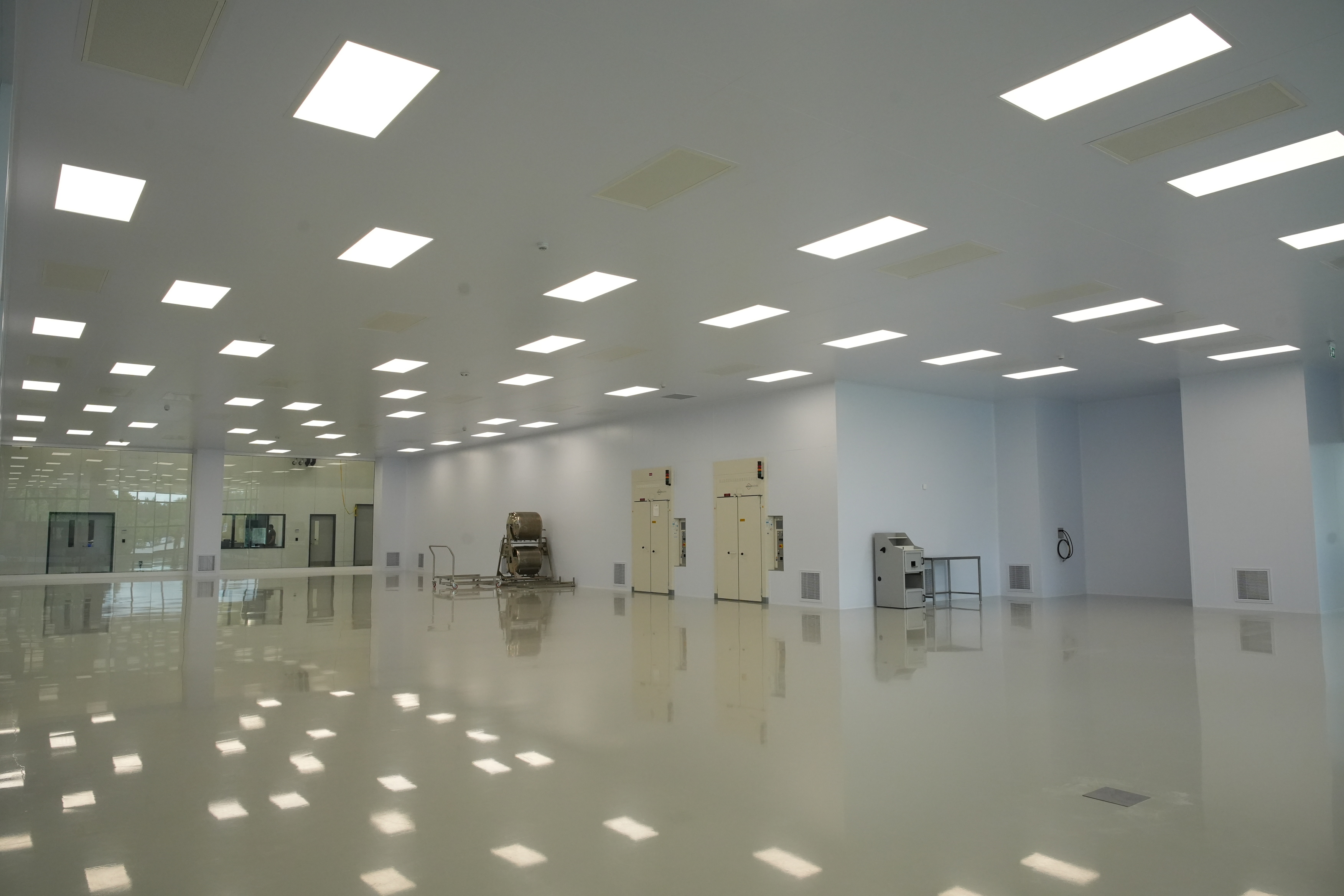 Wide finished ISO Class 8 production floor with process equipment, LED ceiling panels and reflective epoxy flooring — Moddulx panel envelope
