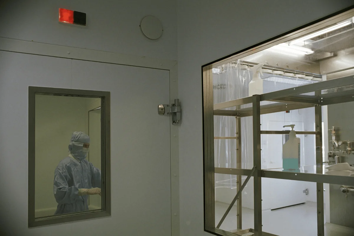 Technician in protective gear working inside a cleanroom.