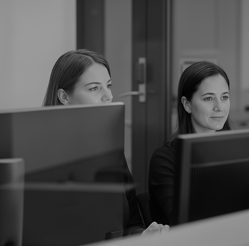 Two women focused on their computer screens in an office setting.