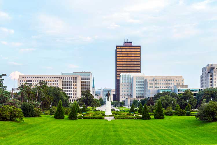 Baton Rouge skyline viewed from the Louisiana State Capitol grounds with manicured gardens and statue in the foreground