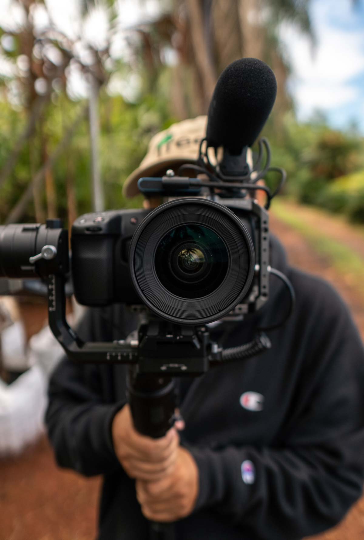 Videographer holding a professional camera with shotgun microphone in an outdoor setting