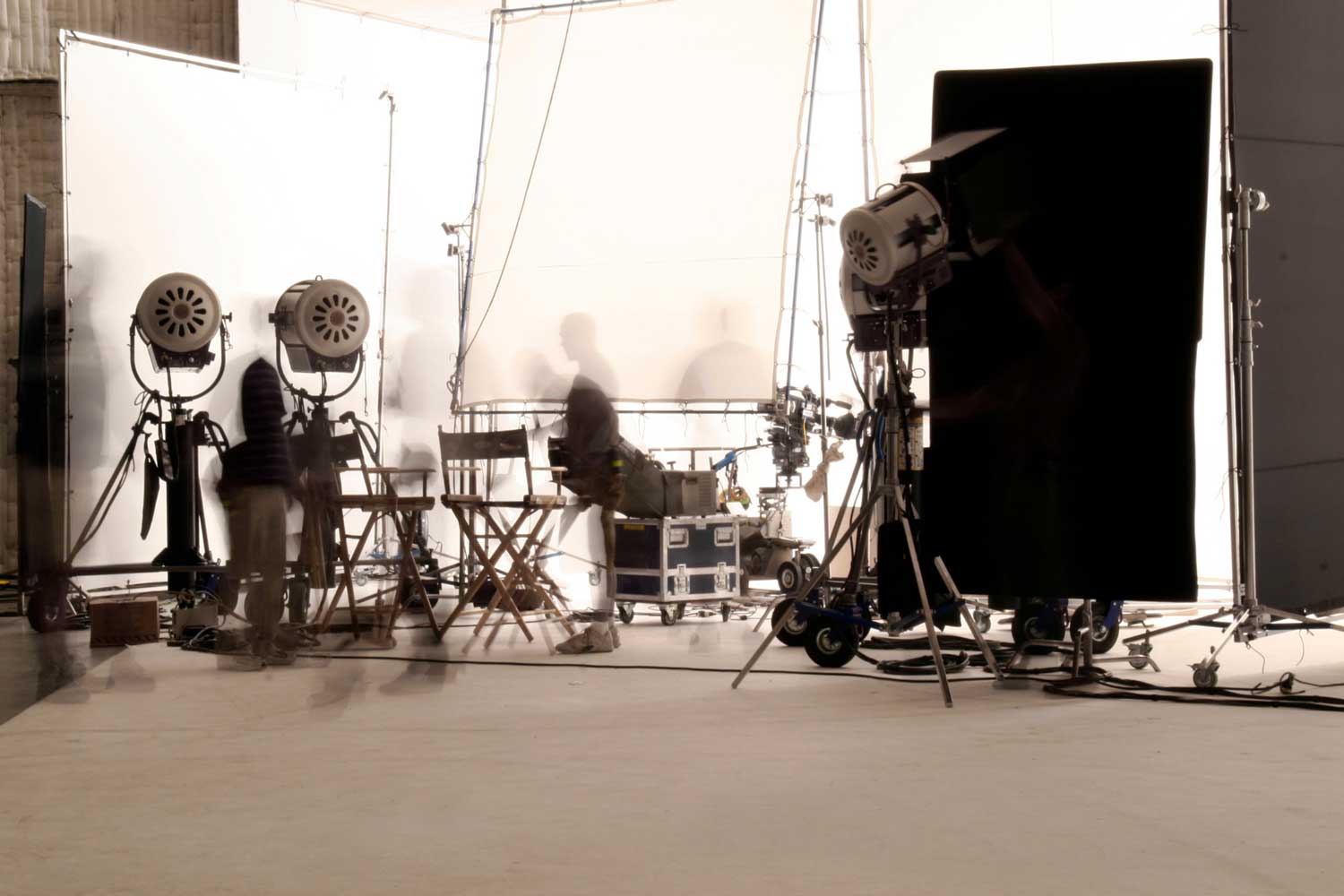 Film crew setting up studio lighting equipment and camera rigs on a professional production set
