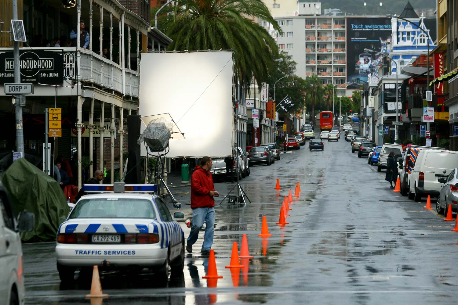 Film production vehicles and equipment blocking a city street with traffic cones during an on-location shoot
