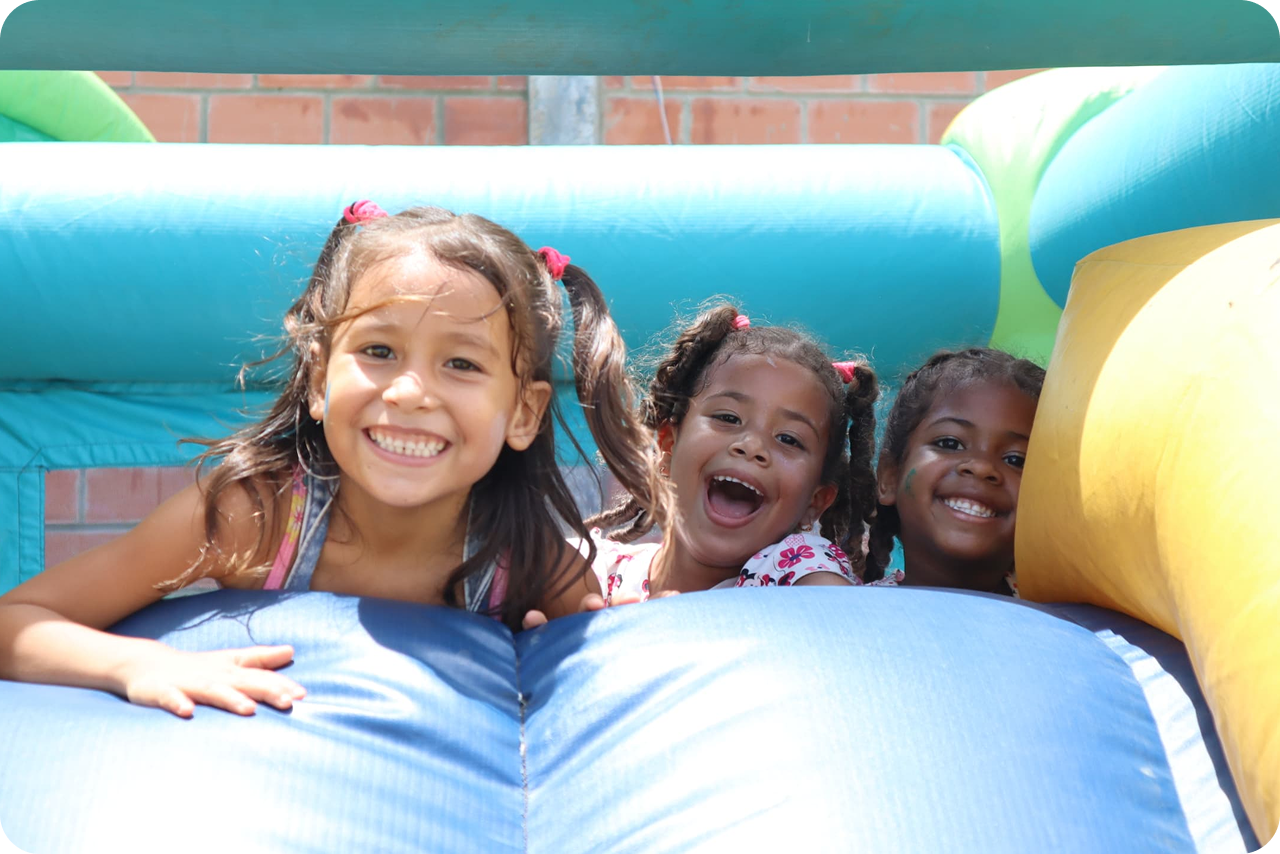 Three smiling girls playing on an inflatable slide at a foundation activity