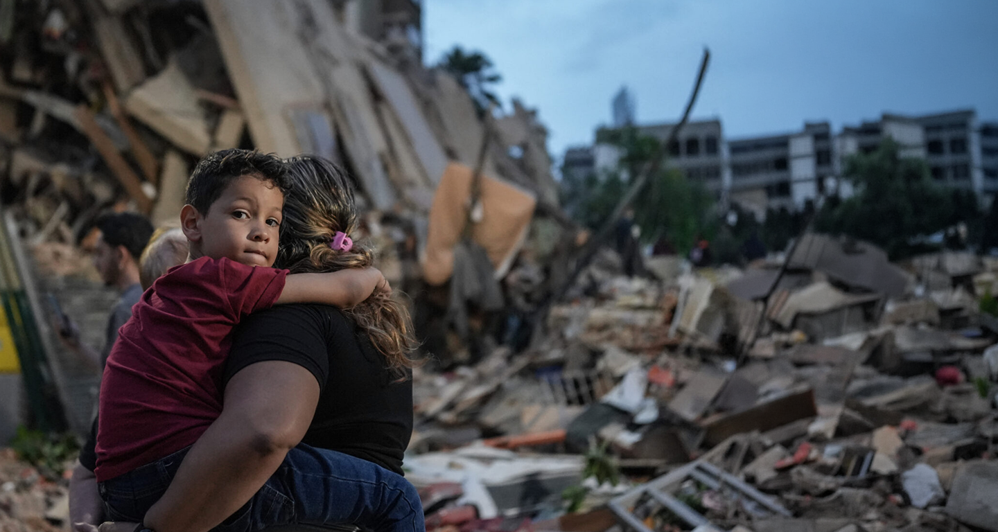 A man carrying a child away from a building destroyed by the earthquakes in Venezuela.