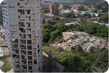 A damaged apartment tower standing above the surrounding city.