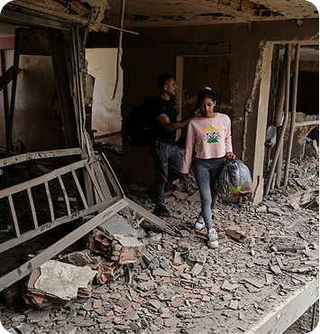 Two people walking out of a building wrecked by the earthquake.