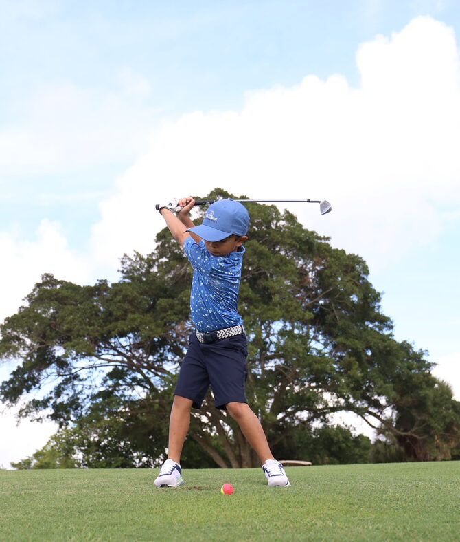 A young golfer taking a swing at the 2025 charity golf tournament.