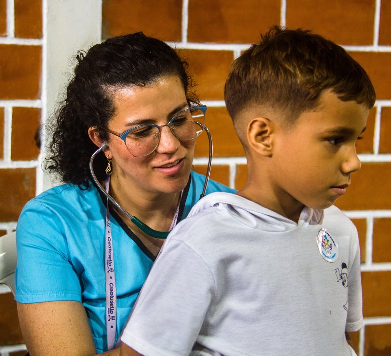 A doctor listens to a boy's chest with a stethoscope at a Victoria Venezuela Foundation medical clinic.