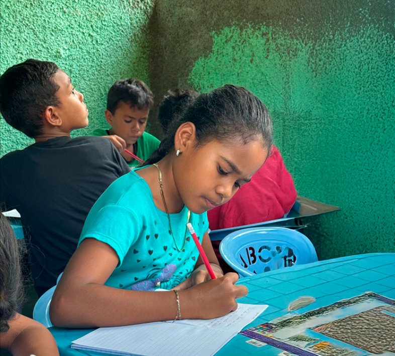 Children doing schoolwork at a table in one of the foundation's programs in Venezuela.
