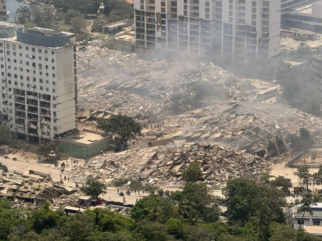 Aerial view of collapsed buildings and rubble, with dust rising, after the earthquakes.