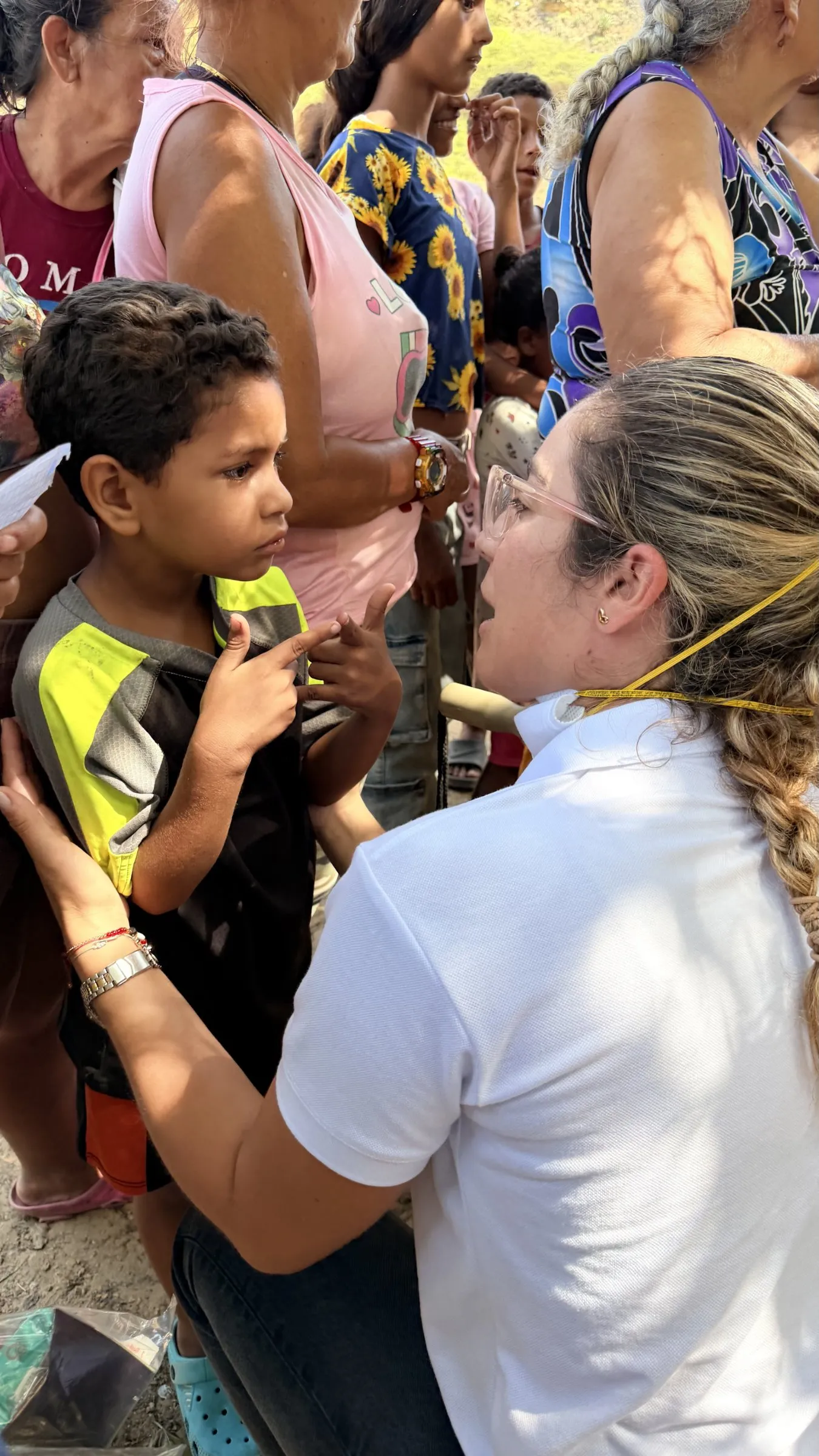 A woman speaks with a young boy in a crowd of families.