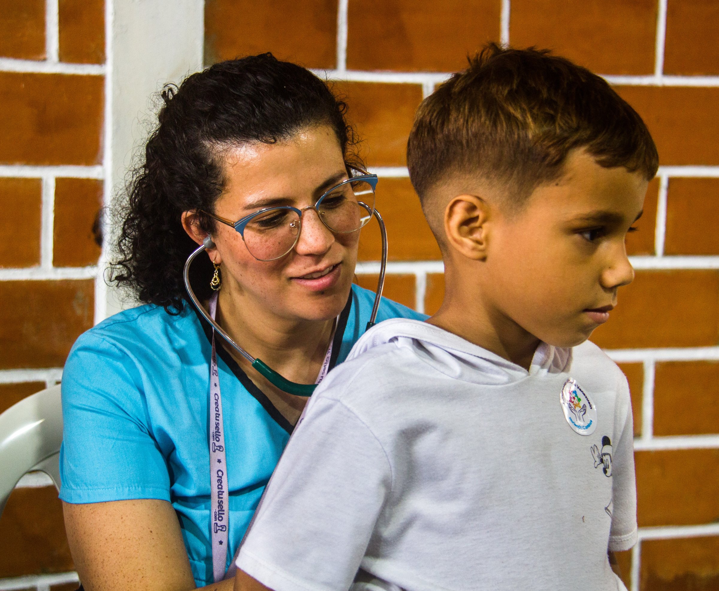 Una doctora voluntaria ausculta a un niño con un estetoscopio en una jornada de atención médica.