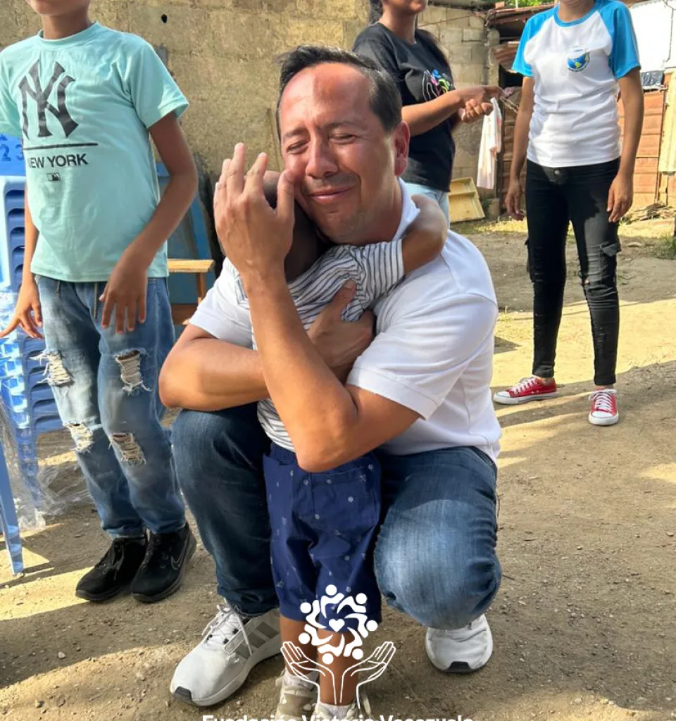 A man hugs a young child at a community gathering in Venezuela