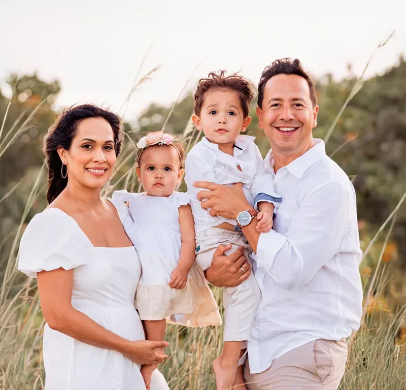 Randy and Helen with their three young children, outdoors in tall grass