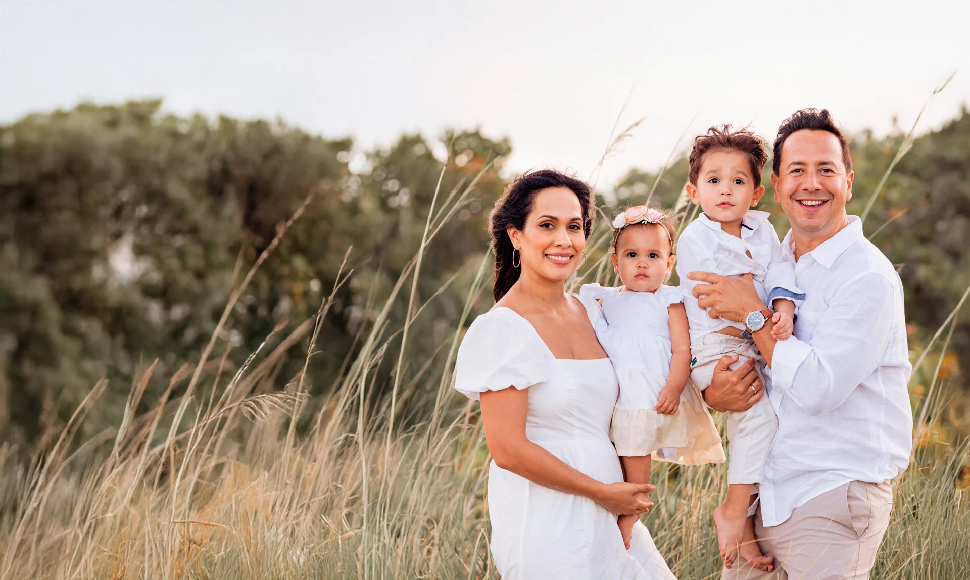 Randy and Helen with their three young children, outdoors in tall grass