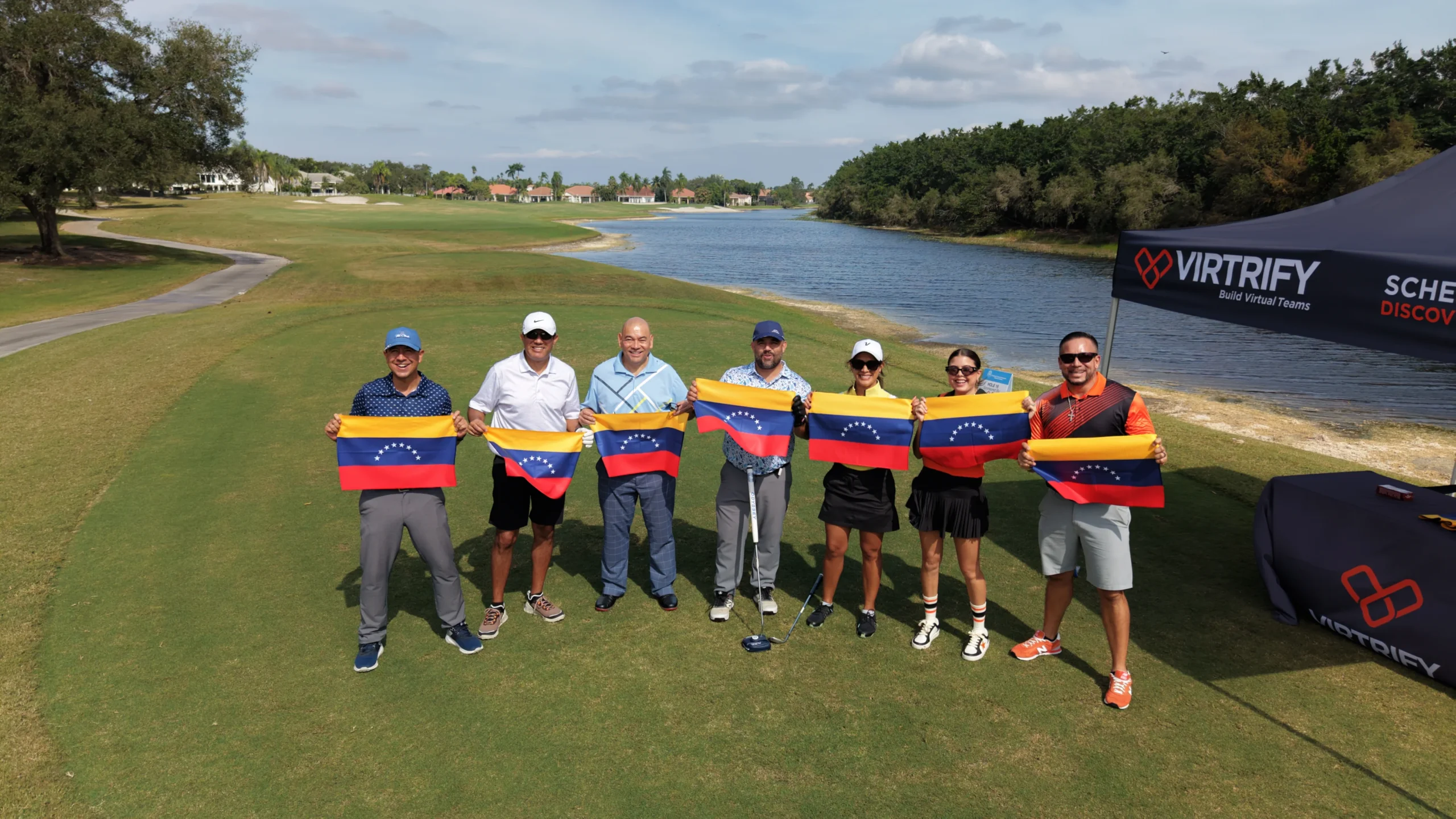Golfistas junto al lago del campo, con banderas de Venezuela.
