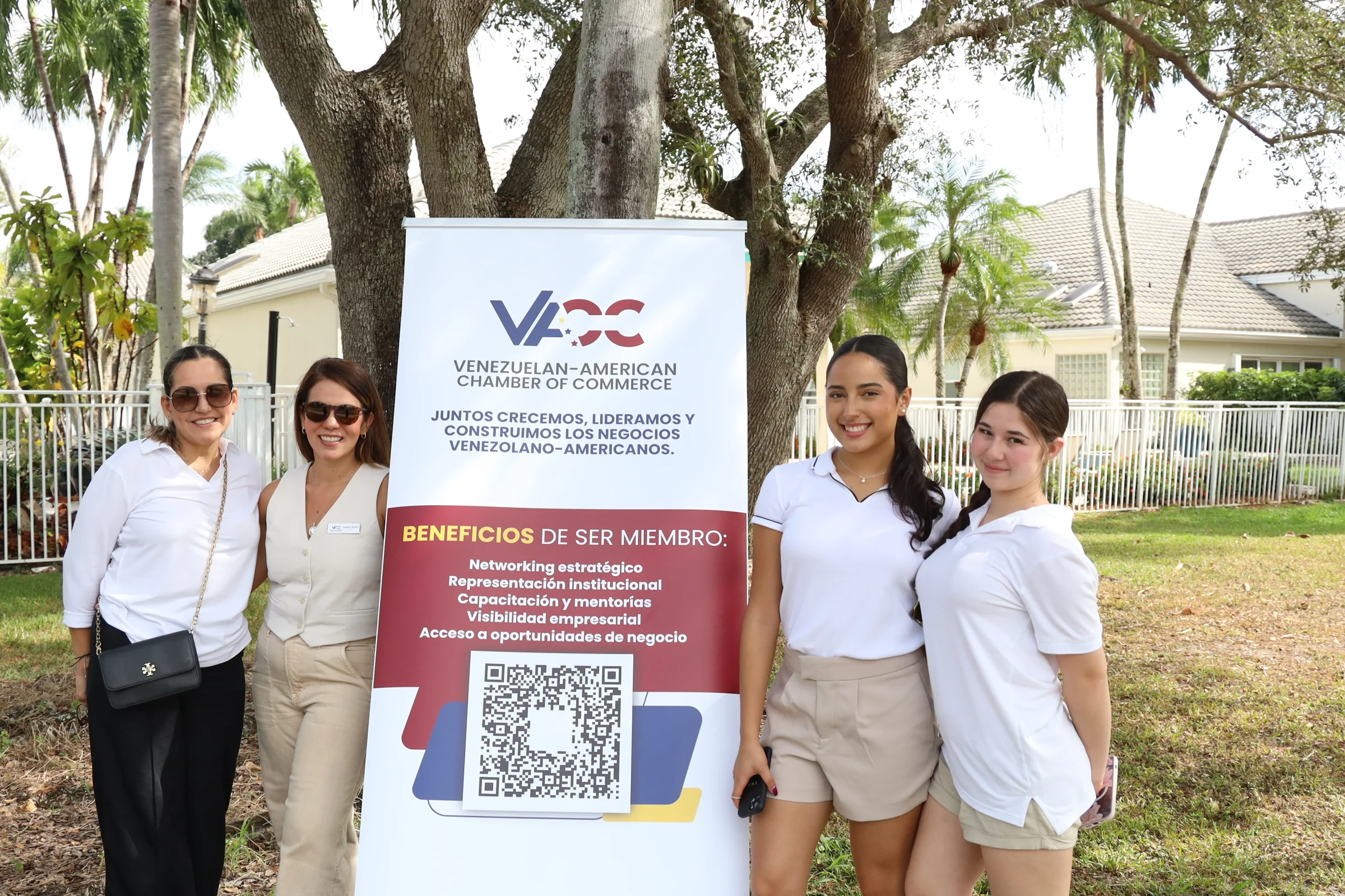Tres voluntarios junto al letrero de un patrocinador en el campo.