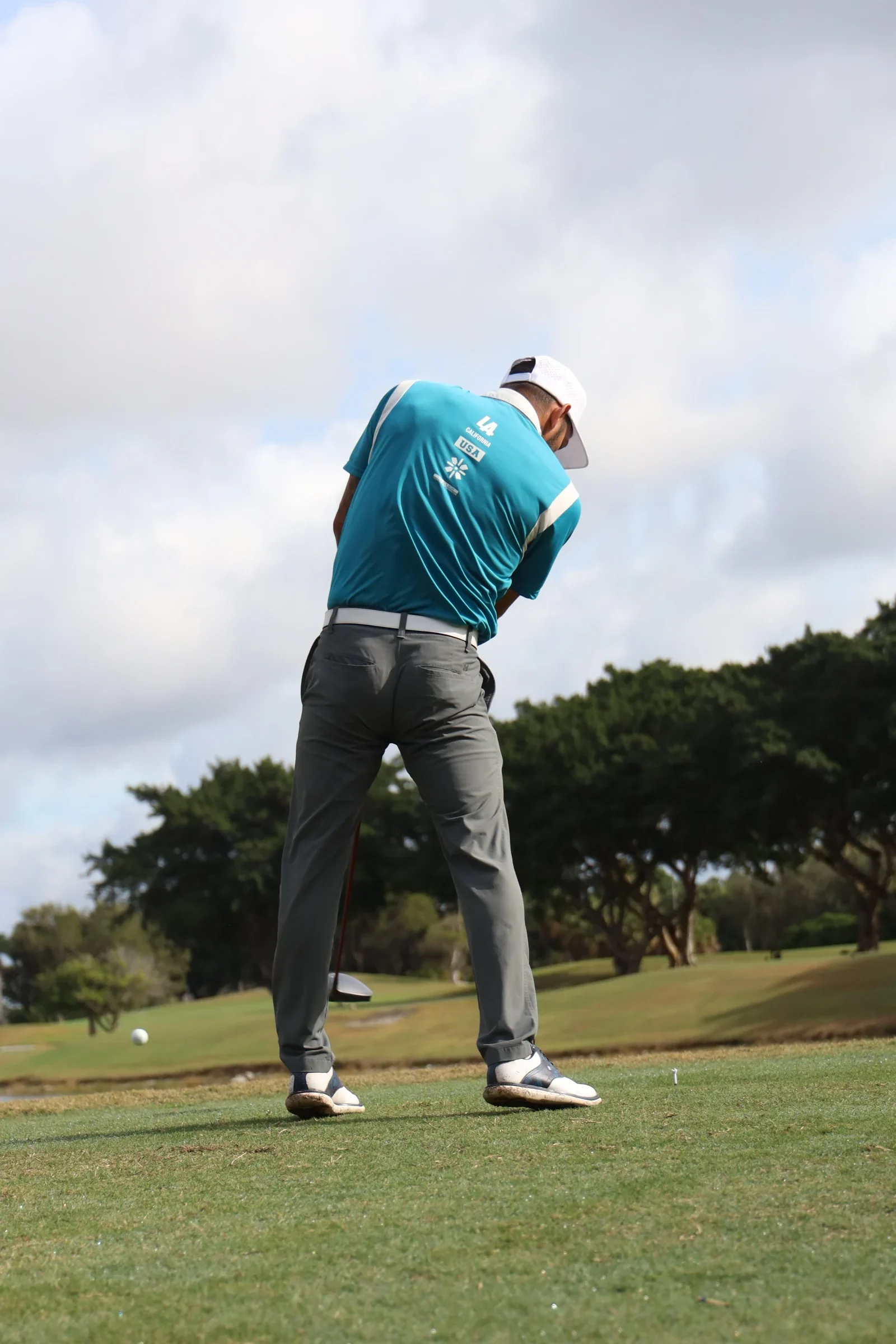 Un golfista termina su golpe desde el fairway.