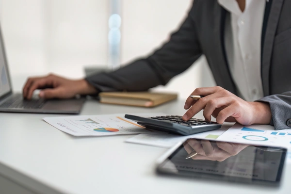 Man in suit working on a laptop and using a calculator
