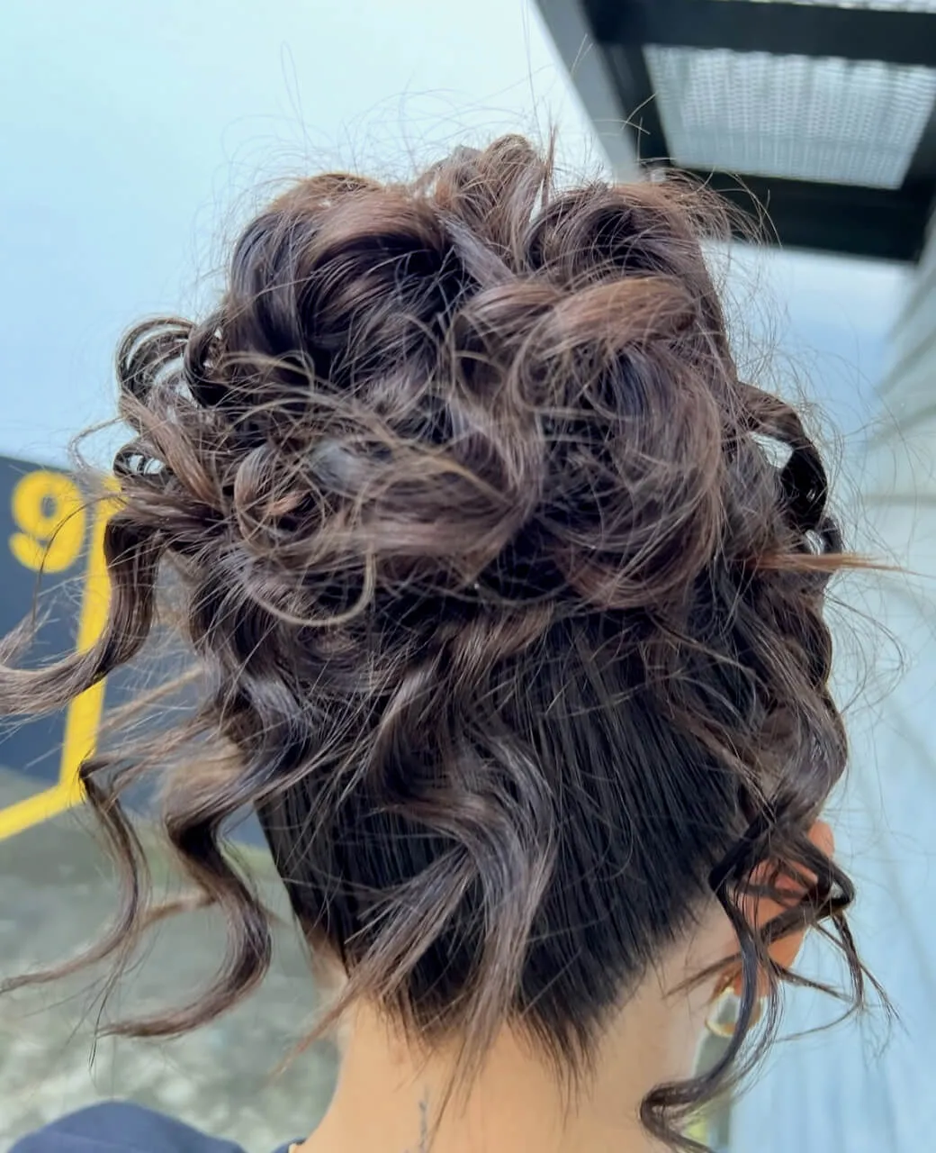 Curly textured high bun upstyle for a special event by Jura Draco Gold Coast hair styling specialists