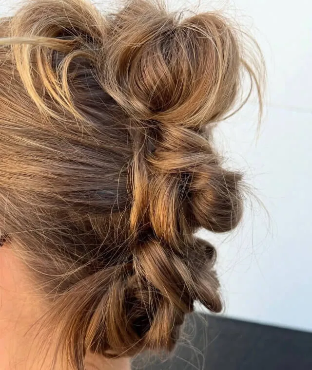 Side view of blond hair styled in multiple loose twisted knots along the back of the head.