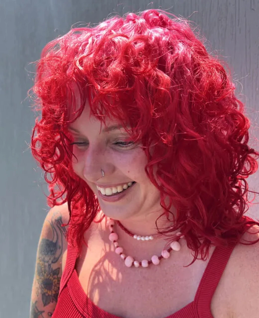 Vivid red curly creative colour with a fringe at Jura Draco Gold Coast creative colour salon