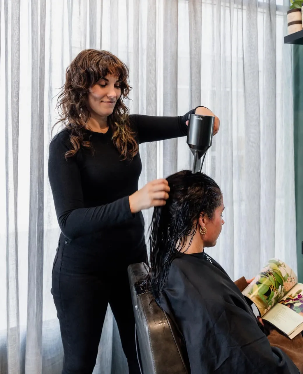 Hairstylist blow-drying a client's hair with a diffuser at Jura Draco Gold Coast salon