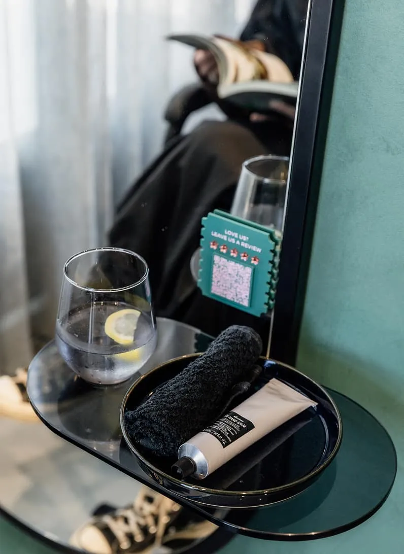 Glass of water, review card and head spa products beside a relaxing client at Jura Draco Gold Coast