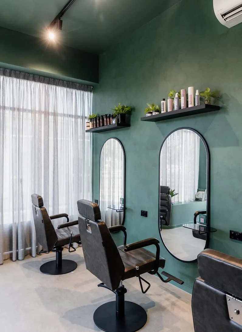 Interior of Jura Draco hair studio with green walls, styling chairs and arched mirrors on the Gold Coast